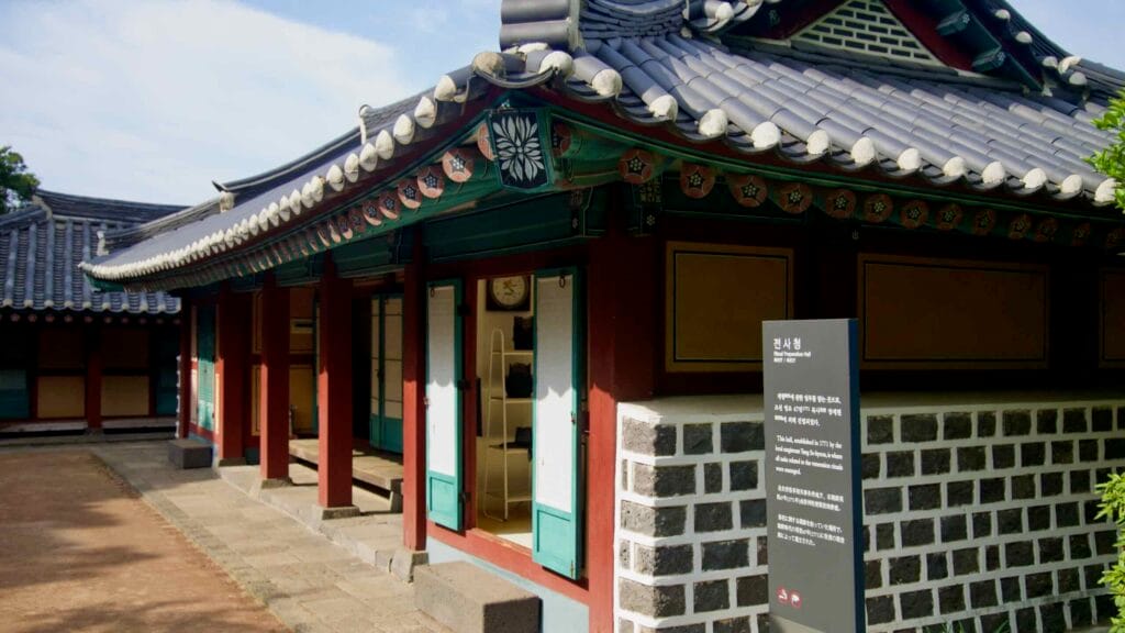 The exhibition hall stands with open doors, tiled eaves, and a signboard.