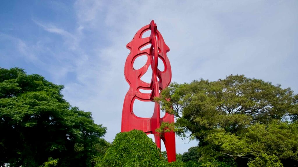 A tall red abstract sculpture rises in Sinsan Park near Samseonghyeol.