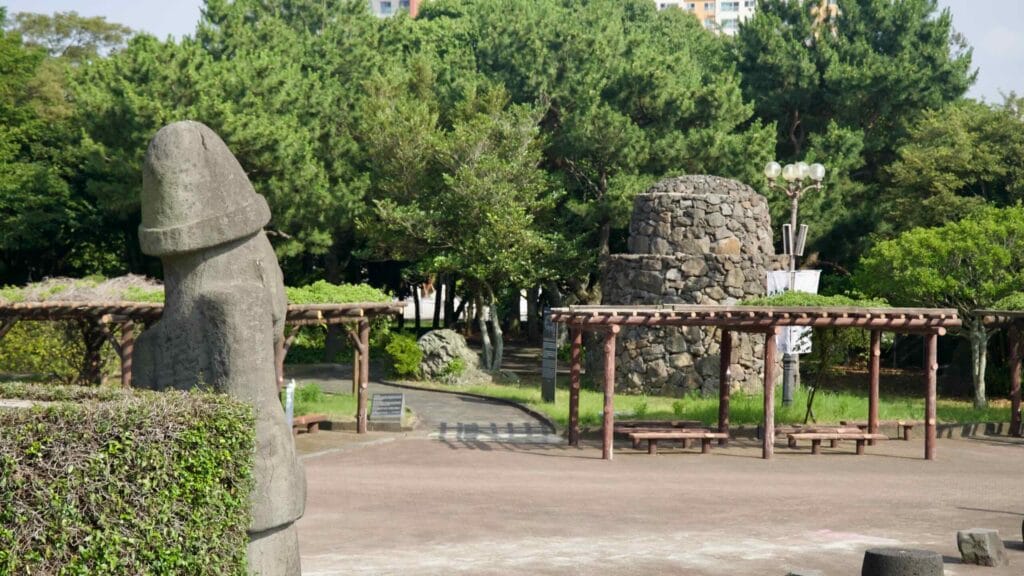 Pergola shelters and a cylindrical stone beacon tower stand in the plaza.