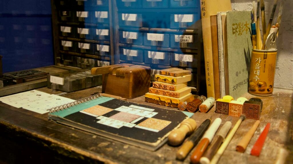 Seal-carving and printing tools sit on a workbench.