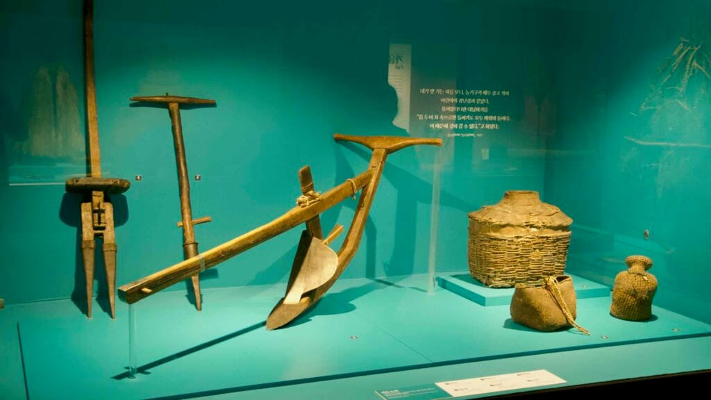 A plow, hand tools, and woven baskets illustrate traditional Jeju farming at the folklore museum.
