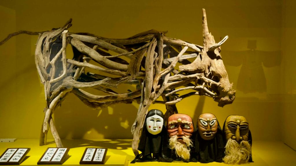 A driftwood ox and carved masks evoke folk ritual and performance at Jeju's folklore museum.