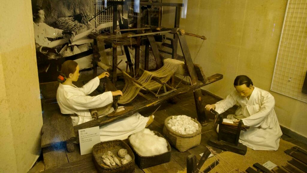 A floor loom and baskets of cocoons illustrate spinning and weaving techniques.