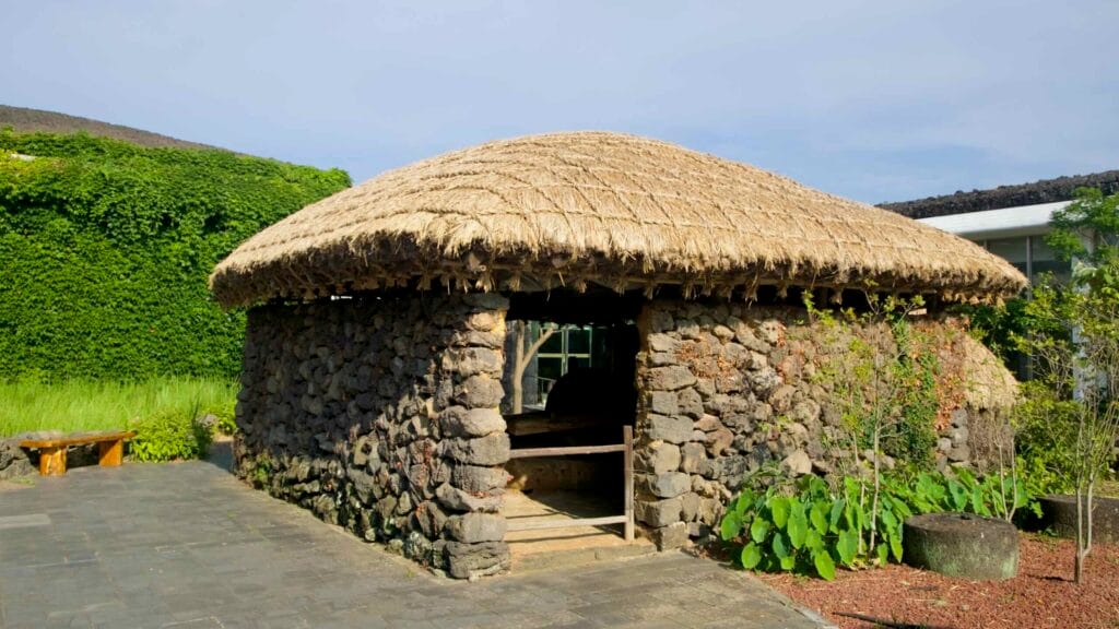 A low stone choga house with a thatched roof stands in the museum courtyard.