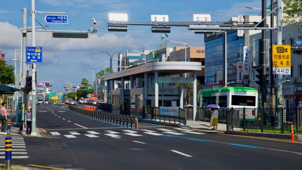 A center-platform BRT station on Seogwang-ro serves downtown, with a green articulated bus.
