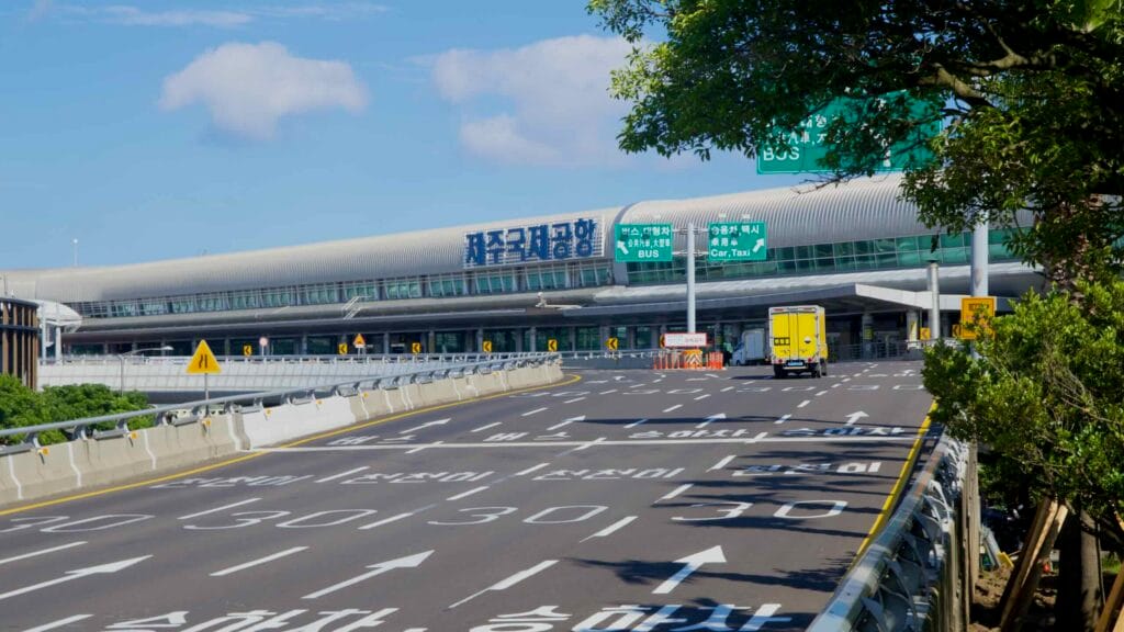Fresh lane markings curve past the airport terminal, with arrows, speed limits.
