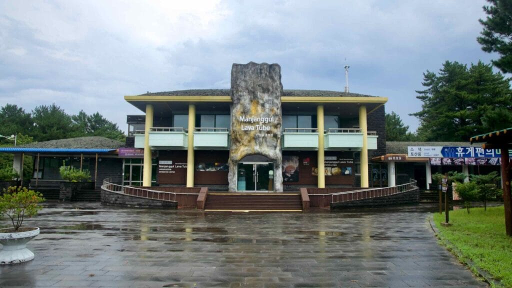 Wide plaza view toward the Manjanggul Lava Tube information center after rain.
