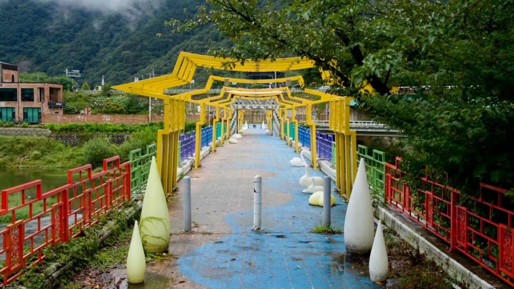 Repeating yellow frames line the Omija Theme Tunnel walkway with a blue deck.