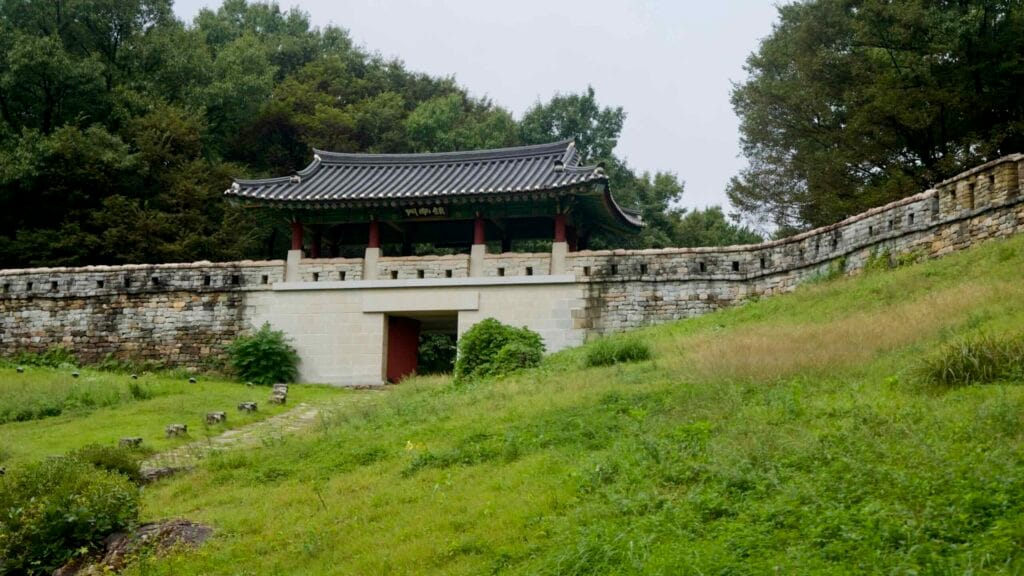 A tiled-roof gate pavilion rises above stone ramparts with a narrow entry and embrasures.