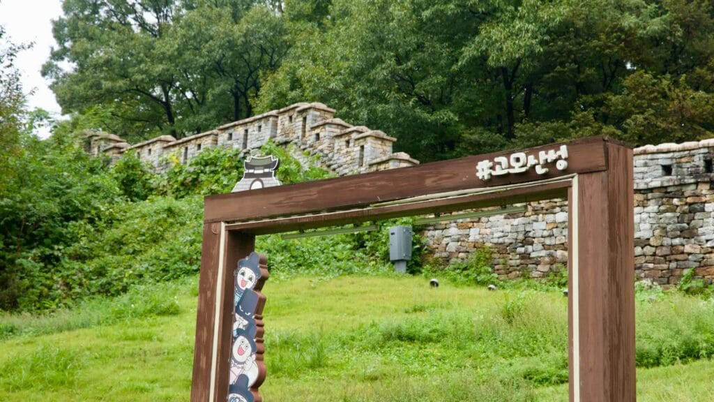 A wood hashtag photo frame stands near stone ramparts on the fortress hillside.