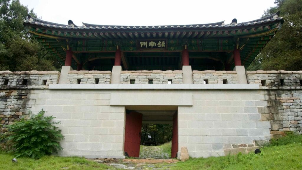Another tiled-roof gate pavilion crowns the rampart above trees and stone steps.