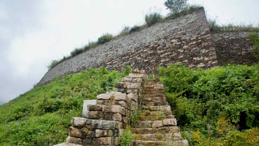 Close stone steps climb toward a massive sloped curtain wall at Gomo Mountain Fortress.