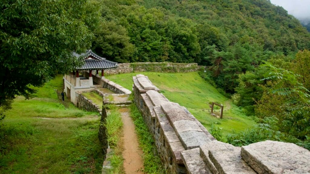 A wall walk crosses a gatehouse at Gomo Mountain Fortress in drifting mist.