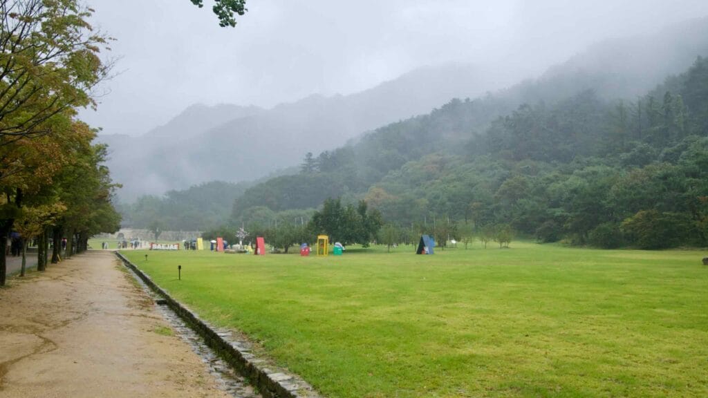 Wide lawns and photo props sit beneath misty mountains in Mungyeong Saejae Provincial Park.