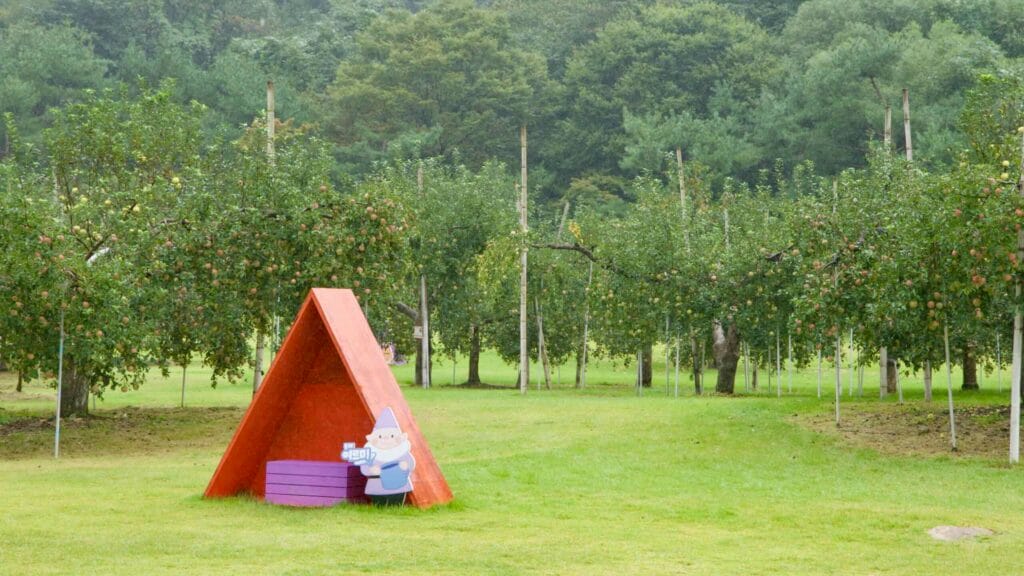 Apple trees and a red photo shelter brighten a grassy field at Mungyeong Saejae Provincial Park.