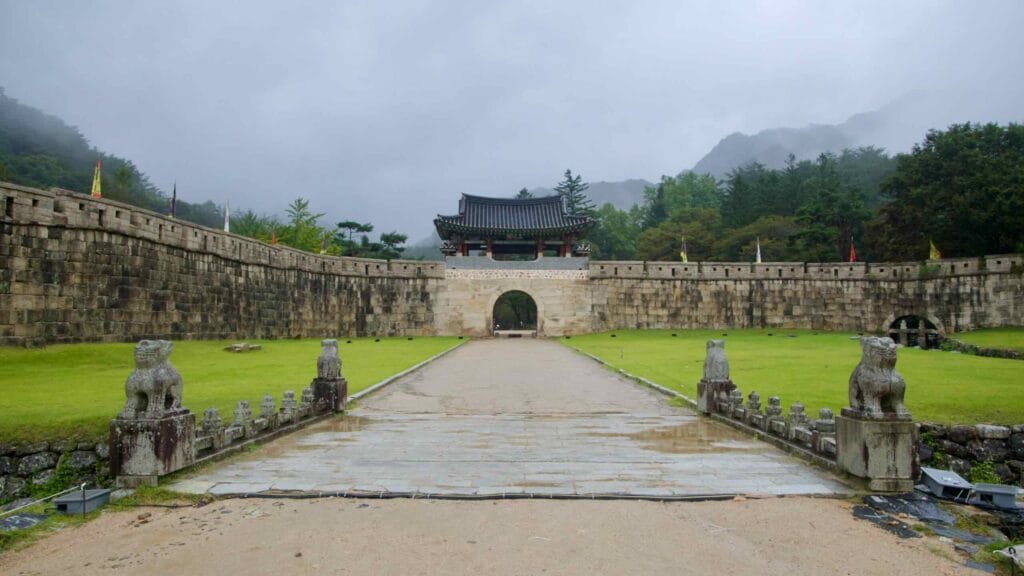 A straight approach leads to the main stone gate and roofed pavilion at Mungyeong Saejae.