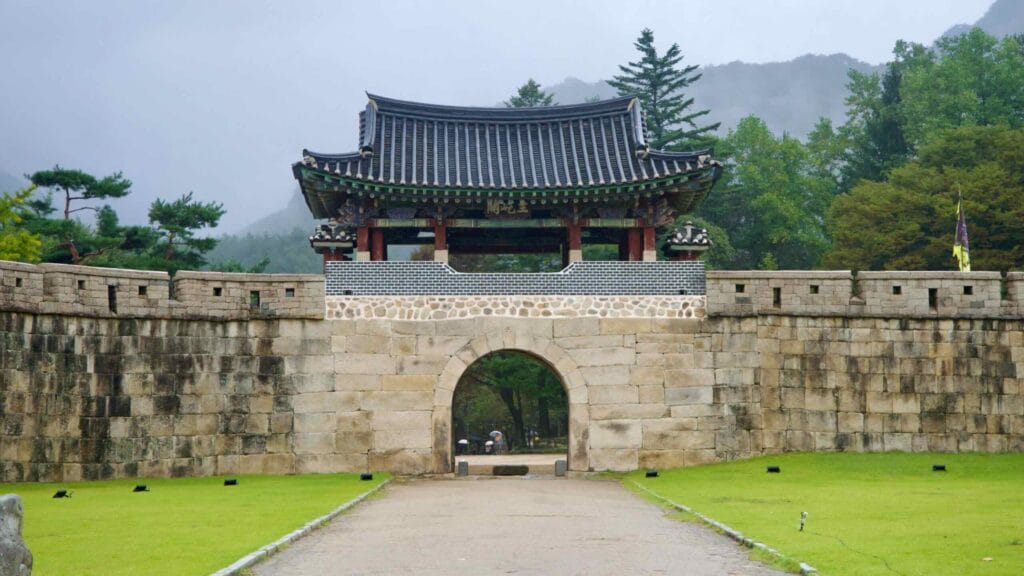 A tiled-roof pavilion crowns a stone wall and arch at Mungyeong Saejae Fortress.