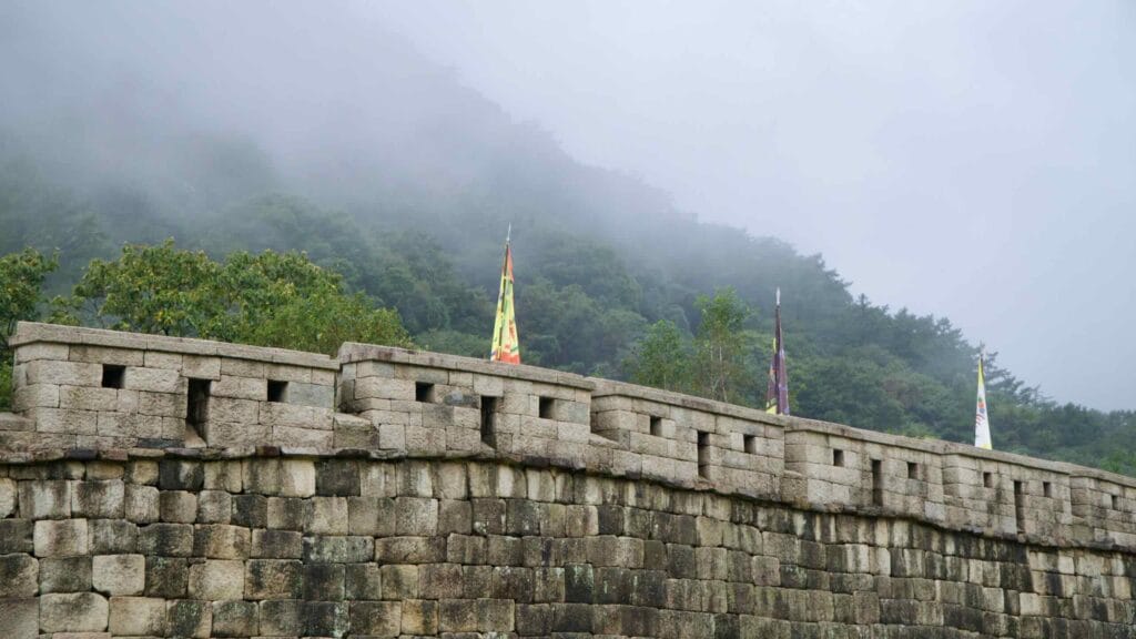 Battlements and banners rise into low cloud at Mungyeong Saejae Fortress.