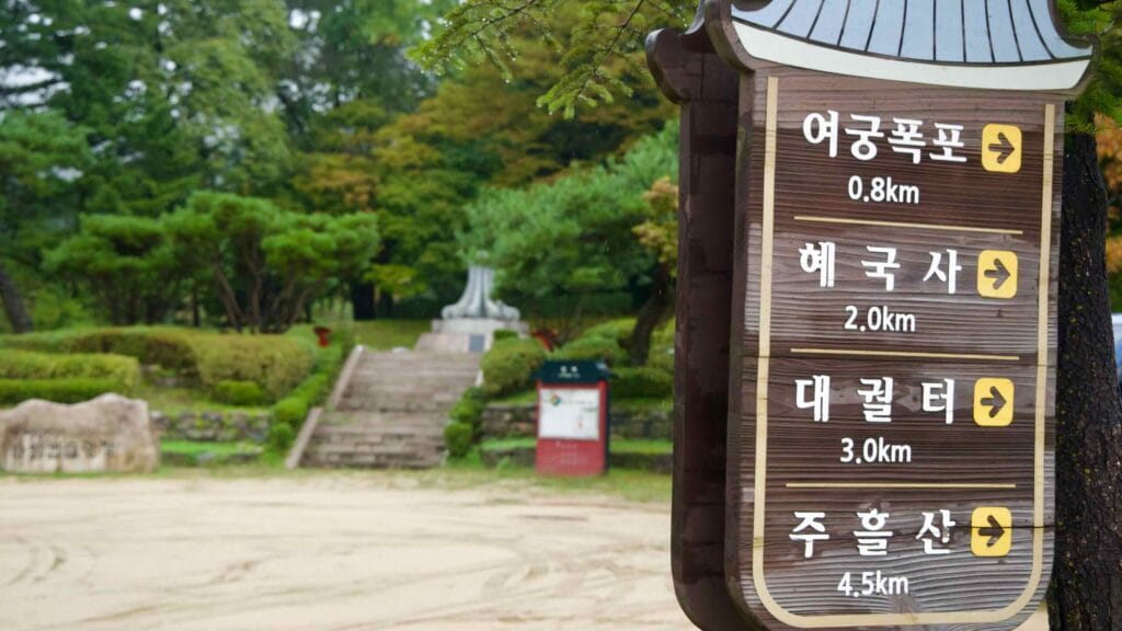 A wooden wayfinding sign lists trail distances at Mungyeong Saejae Provincial Park.