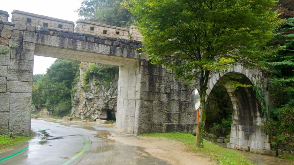 A stone arch bridges a clear creek beside the road at Mungyeong Saejae Provincial Park.