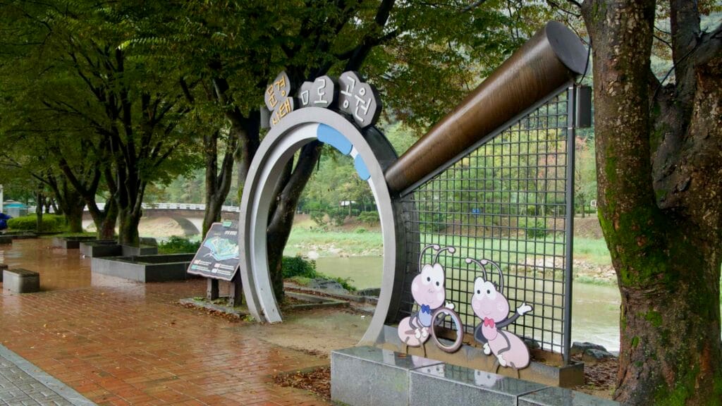 A gateway sign for the Mungyeong Ecological Maze Park stands along the riverside promenade.