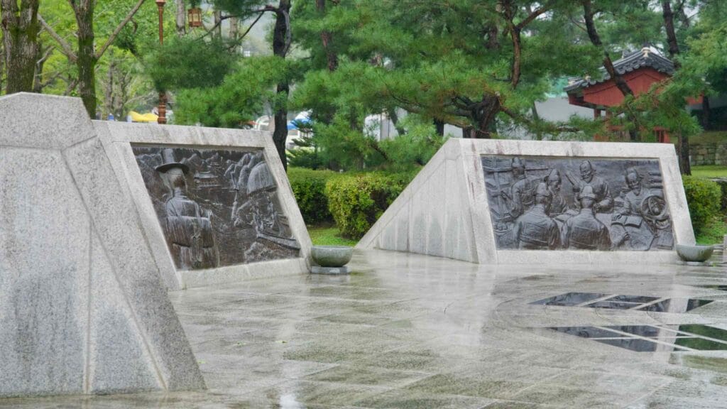 Angled bronze reliefs on granite bases line the plaza at Mungyeong Saejae.