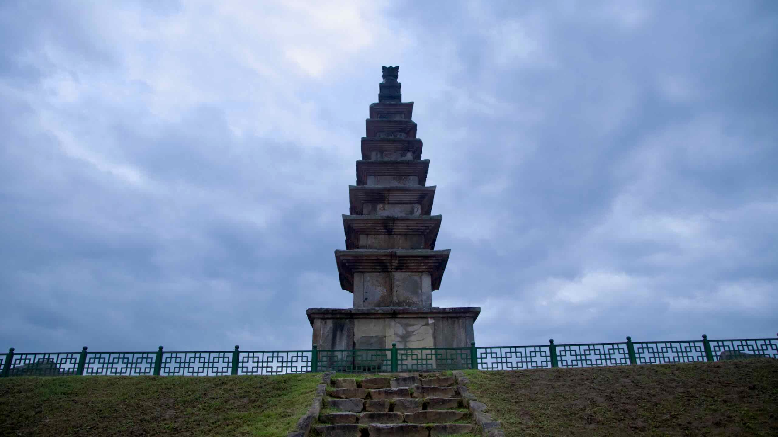 Weathered steps climb to the platform of Jungang Tower beneath a heavy evening sky.