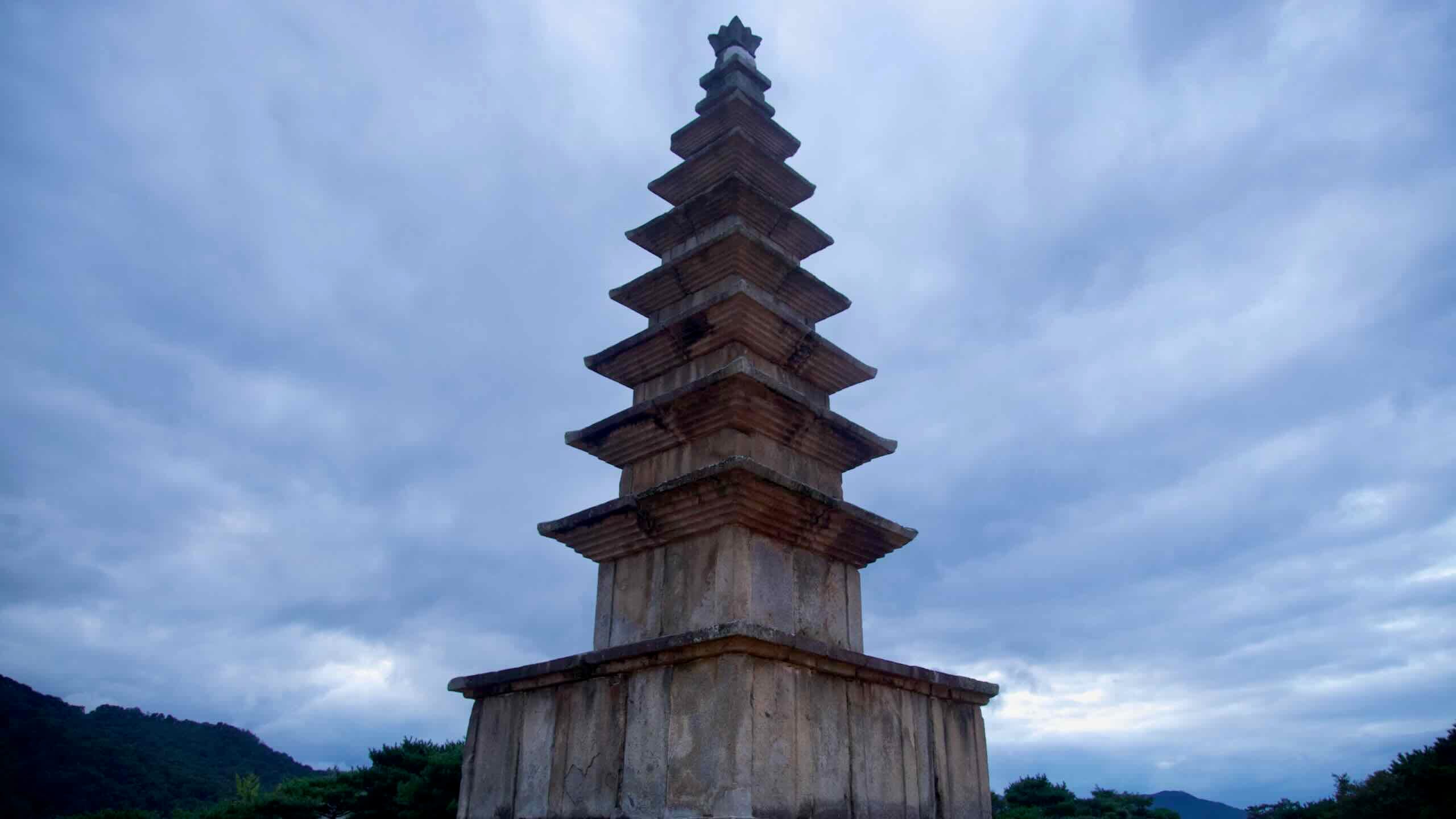 Jungang Tower stands at dusk with a ring of lanterns and forested hills beyond.