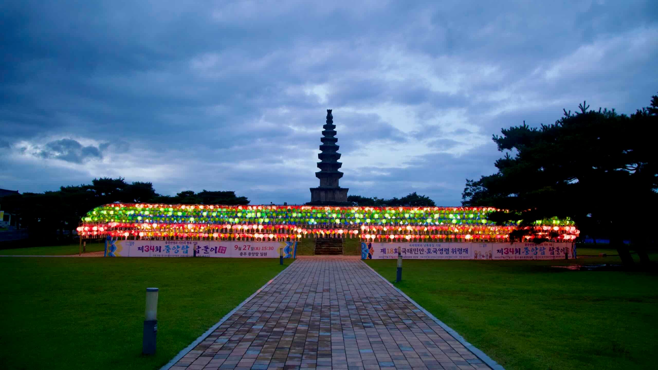 A straight path leads to Jungang Tower with lanterns and event banners lining the lawn.