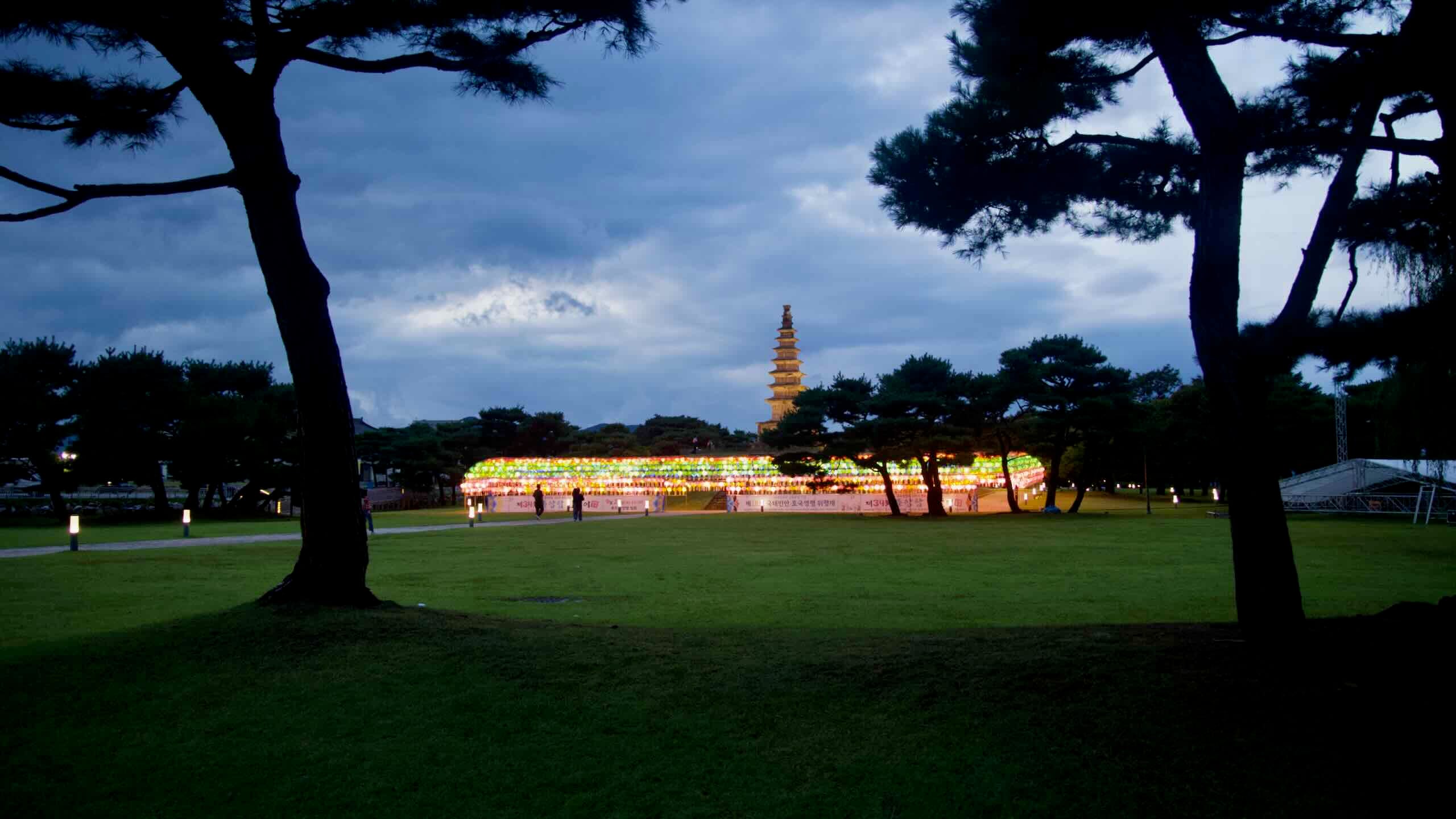 A canopy of multicolored lanterns glows on the lawn below the stone Central Tower.