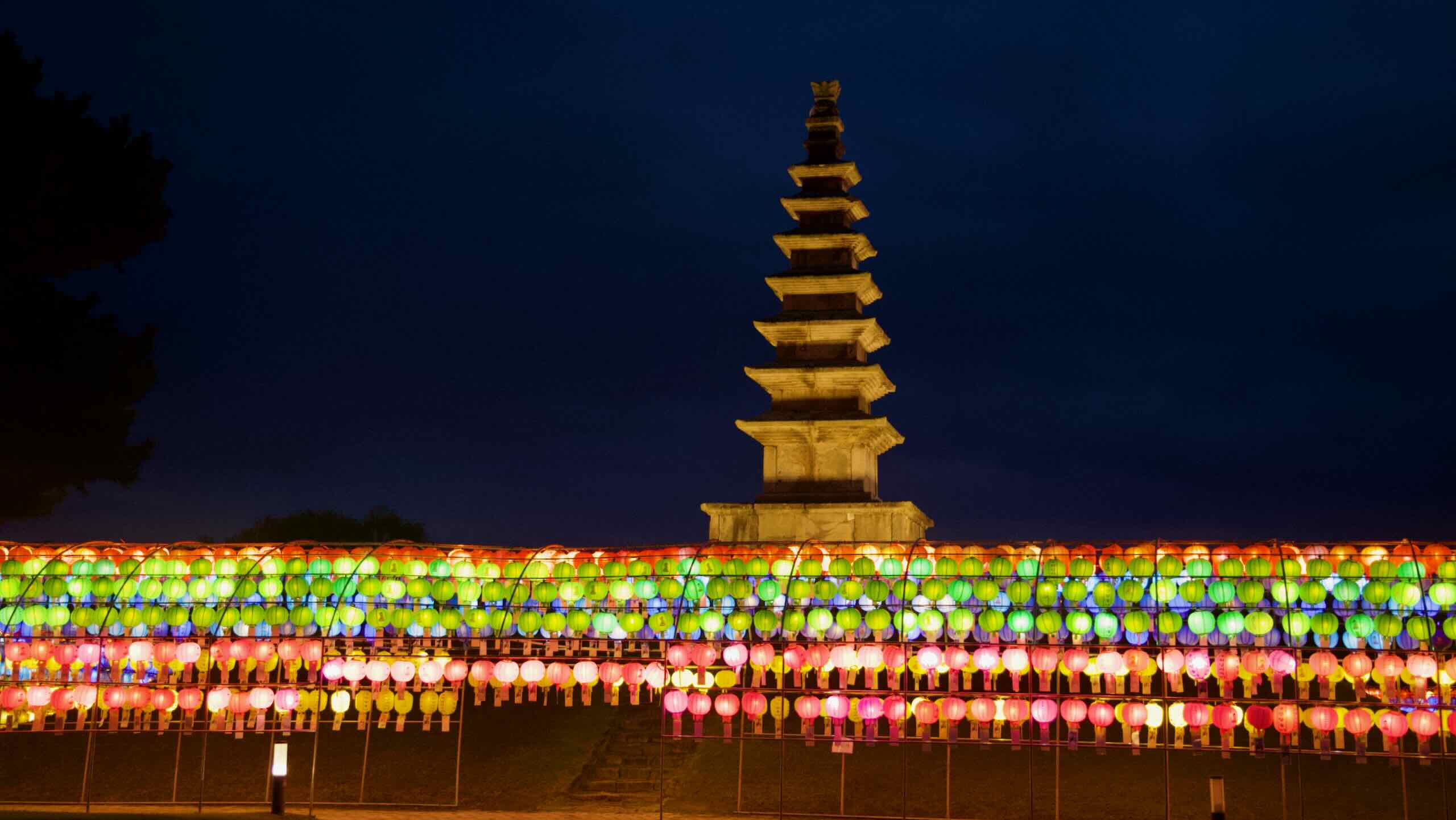 Rows of colorful lanterns form a bright canopy below the stone pagoda at Jungangtap Park.