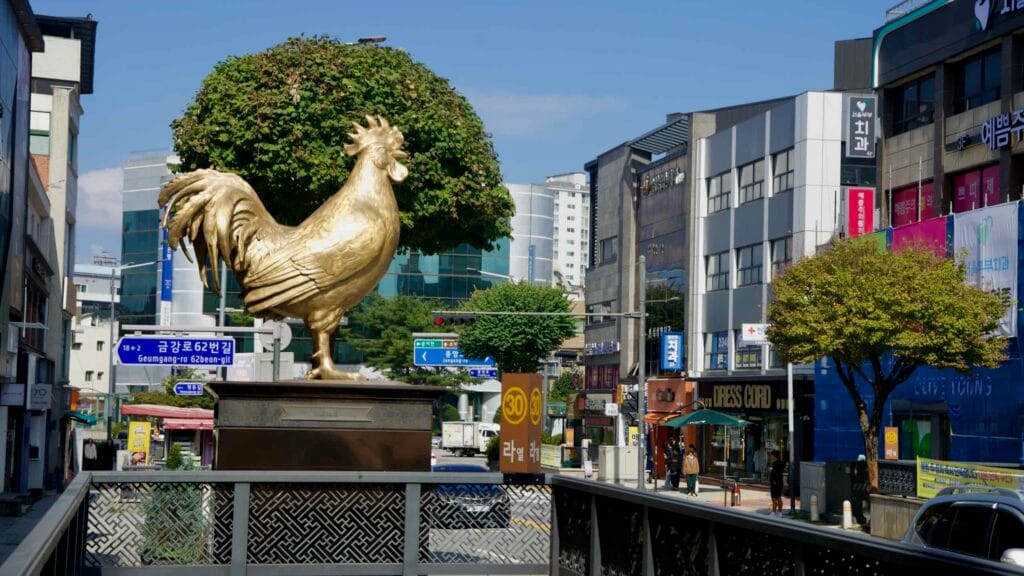 A golden rooster statue stands above railings at the entrance to the underground shopping mall.
