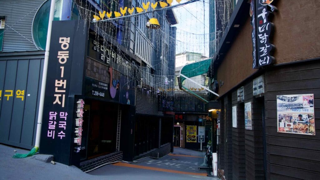 The entrance to the Myeongdong dakgalbi alley is marked by glowing signs and chicken icons.