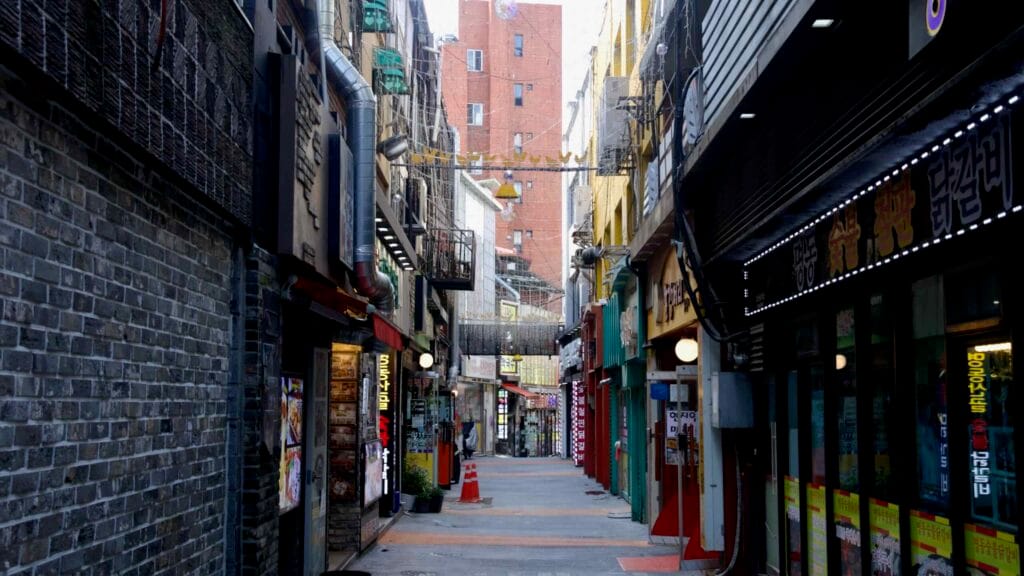 A restaurant lane lined with exhaust ducts runs behind kitchens in Chuncheon’s food district.