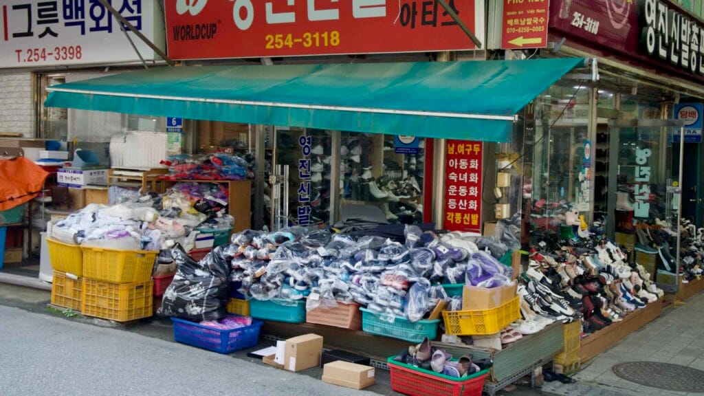 A shoe store at Chuncheon Central Market displays piles of packaged footwear and rows of sneakers spilling onto the sidewalk.