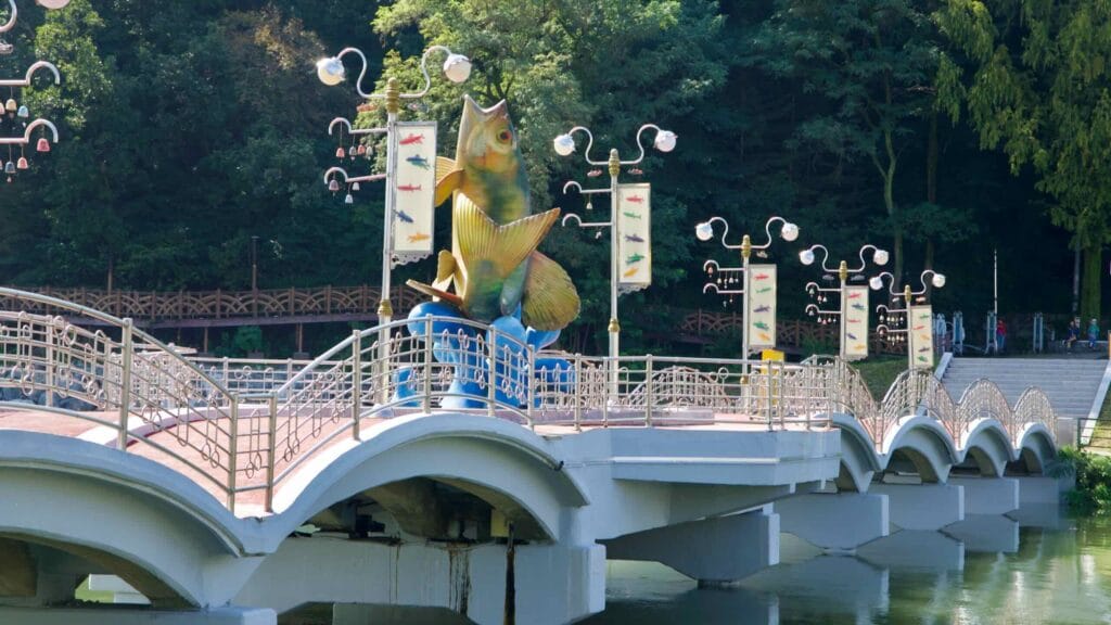 A large fish sculpture crowns the arched bridge over Gongji Stream, flanked by decorative lampposts and banners.