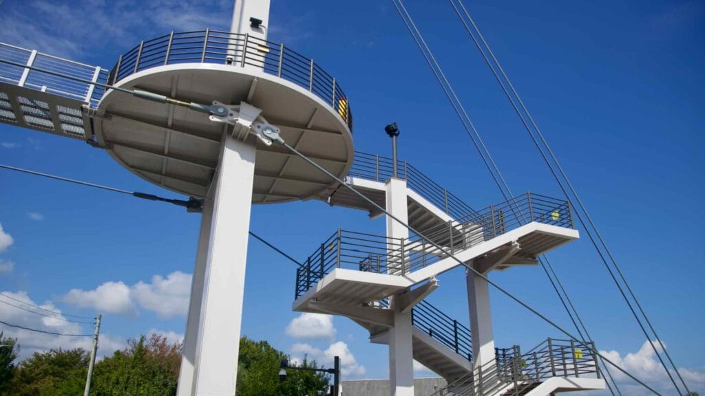 The tower and staircases of Chuncheon Sairo 248 footbridge rise above the riverside, with suspension cables and an elevator shaft.