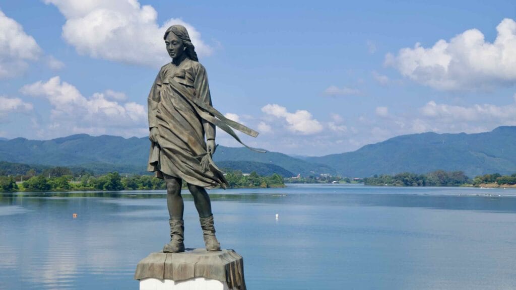 The Soyang River Maiden statue and a carved lyric stone stand on a riverside terrace in Chuncheon.