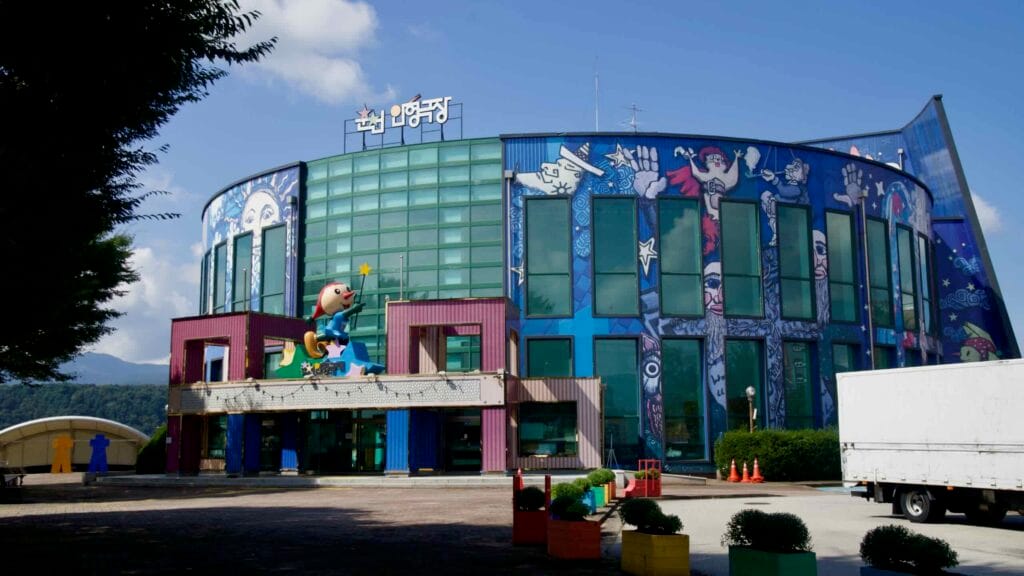 The mural-covered Chuncheon Puppet Theater faces the plaza beside Uiam Lake.