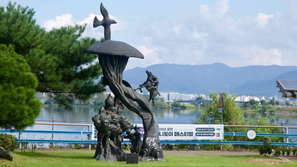 Bronze fantasy sculpture beside Uiam Lake with the city beyond.