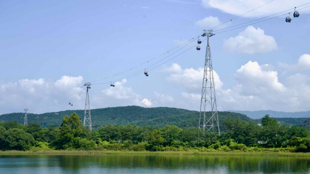 Steel pylons carry gondolas of the Samaksan Lake Cable Car over calm Uiam Lake.