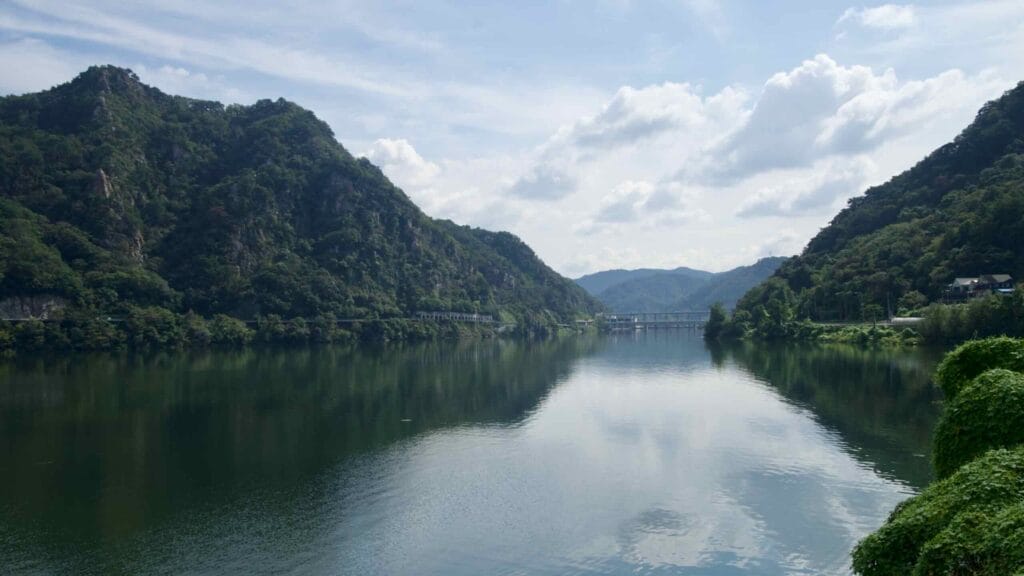 A wide lake valley in Chuncheon leads toward Uiam Dam beneath high clouds.