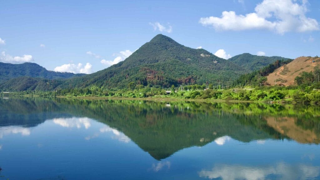 A conical peak reflects cleanly on the still surface of the Bukhangang.