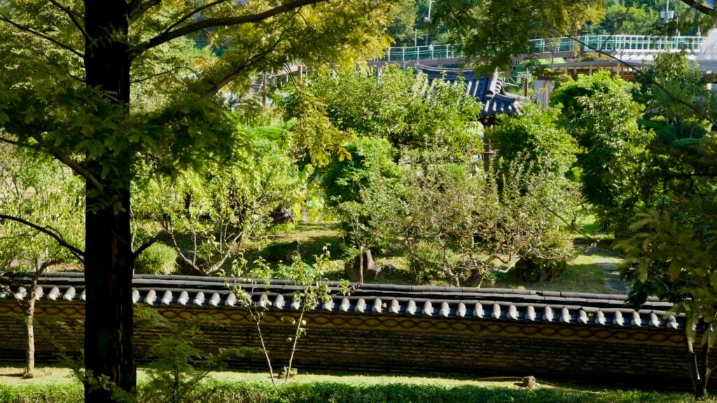 A traditional garden wall and pavilion roof are framed by trees near Jara Island.