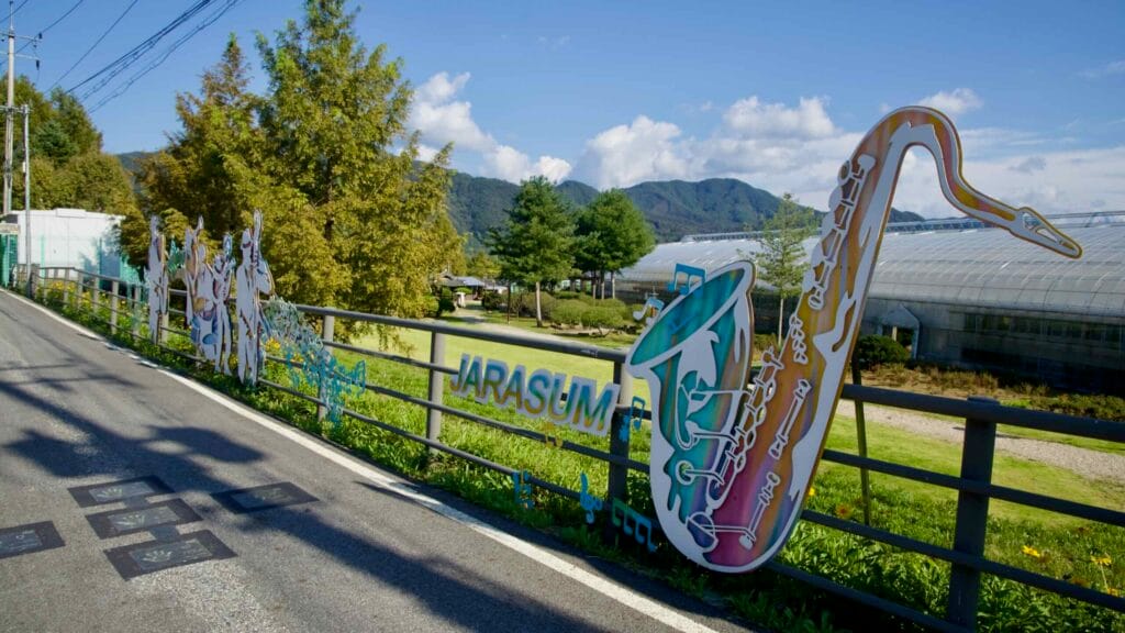 Saxophone-themed JARASUM artwork decorates a roadside fence near the park entrance.