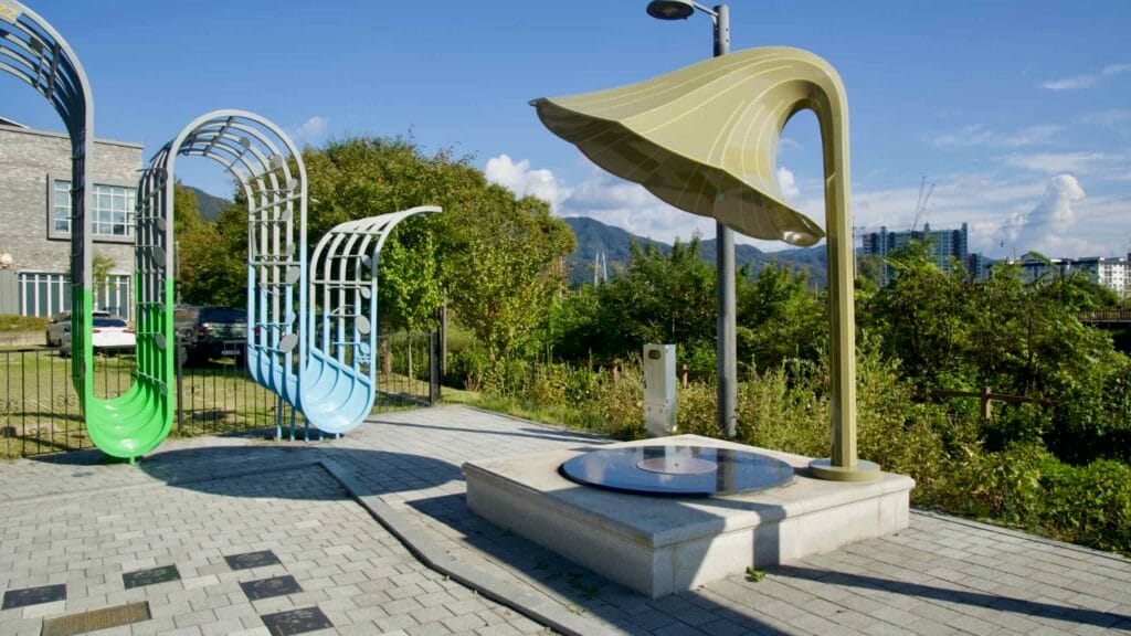 A gramophone sculpture and musical arches stand beside handprint plaques near Jara Island.