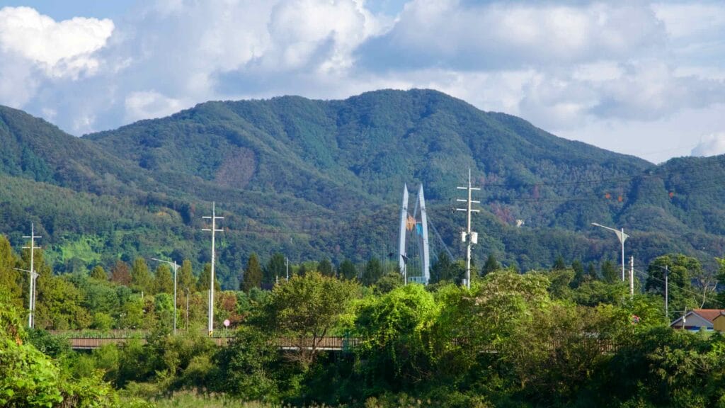 Twin spires of the Jarasum tower rise before forested hills near the Bukhangang River.