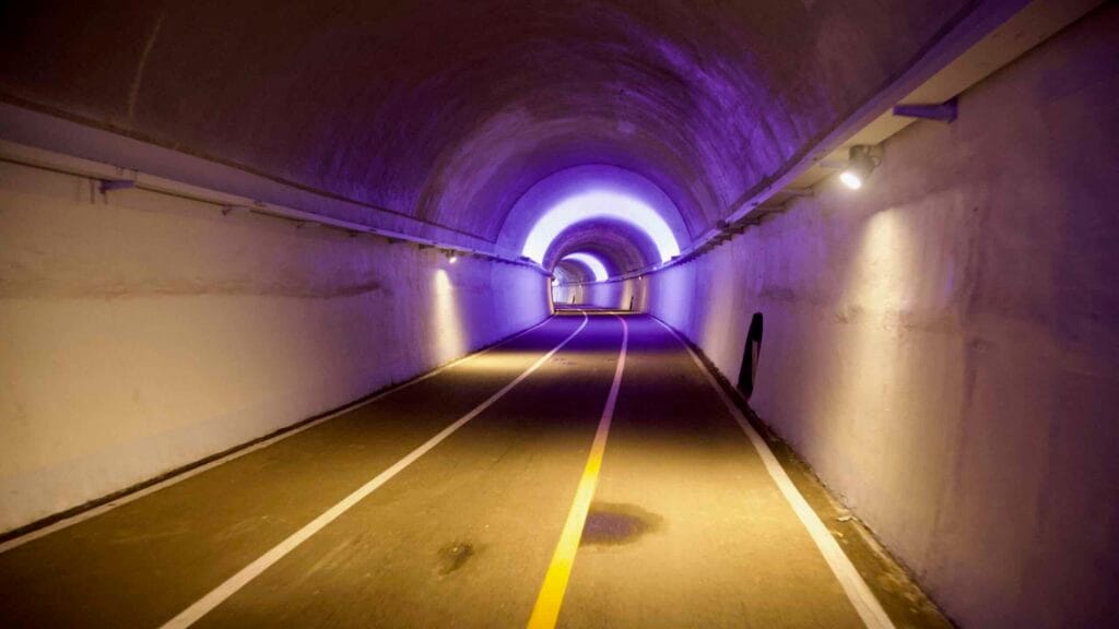 A purple halo glows over a curving lane inside Saekhyeon Tunnel, with spotlights along the walls.