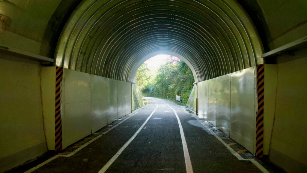 From within Saekhyeon Tunnel, daylight frames the far exit as the bike path bends into forested slopes.