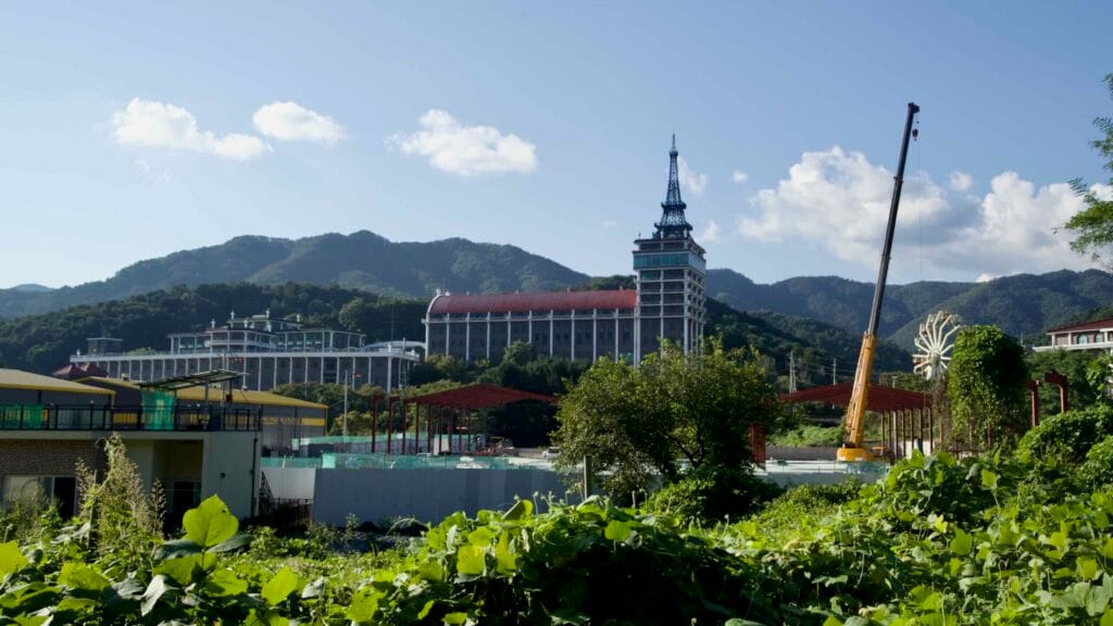 The Cafe Paris complex and tower stand beyond a crane and construction site across the valley.